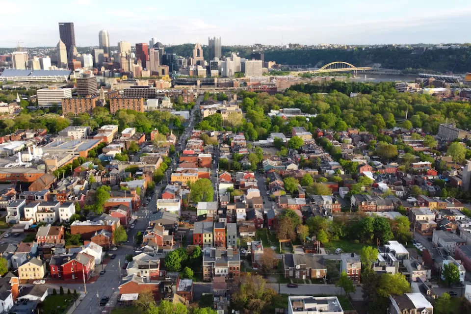 Aerial view of downtown Pittsburgh, Pennsylvania with dense, low-rise housing in foreground.